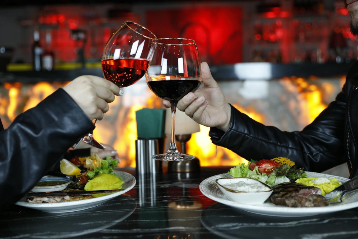 Casal brindando com vinho tinto durante jantar romântico de Dia dos Namorados
