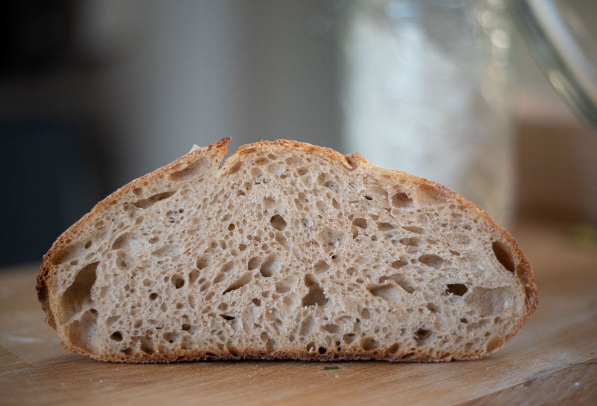Pão de fermentação natural fatiado sobre superfície de madeira